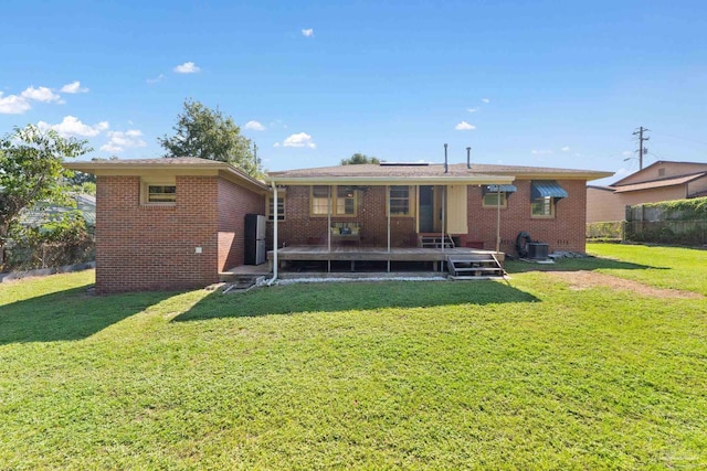 back of property featuring brick siding, fence, and a yard