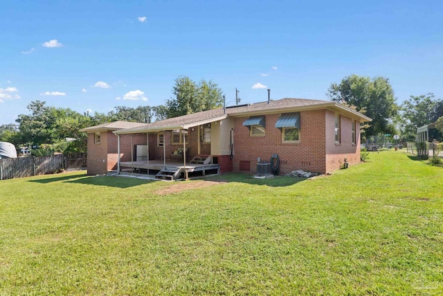 back of property with cooling unit, brick siding, a yard, and fence