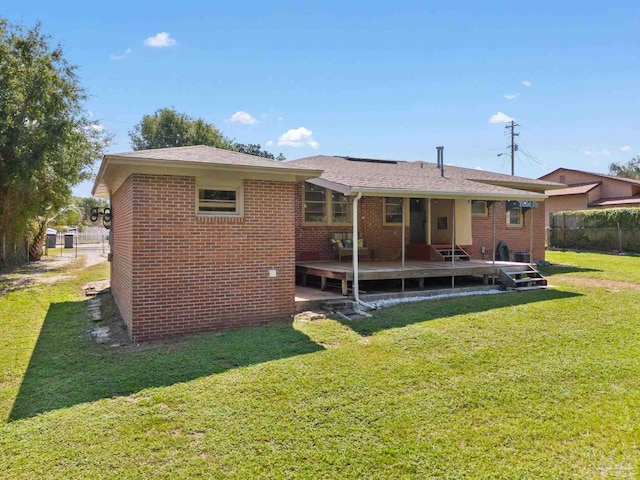 back of property with a yard, fence, a deck, and brick siding