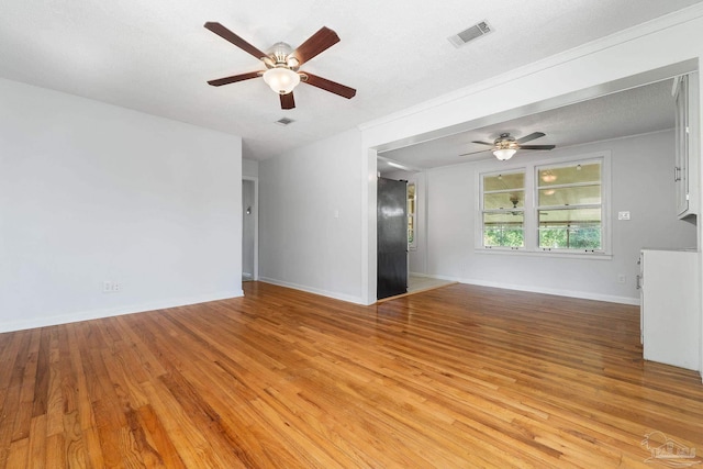 empty room featuring a ceiling fan, light wood-type flooring, visible vents, and baseboards