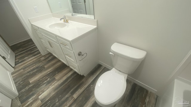 half bathroom with baseboards, toilet, and wood finished floors