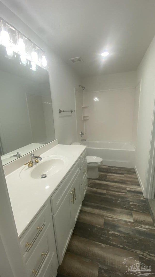full bathroom with visible vents, vanity, wood finished floors, toilet, and shower / bath combination