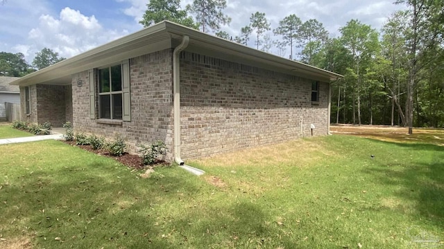 view of side of home with a yard and brick siding