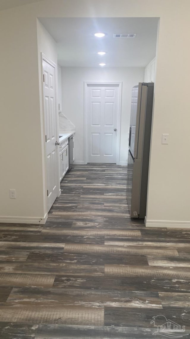 hallway featuring baseboards, dark wood finished floors, and visible vents