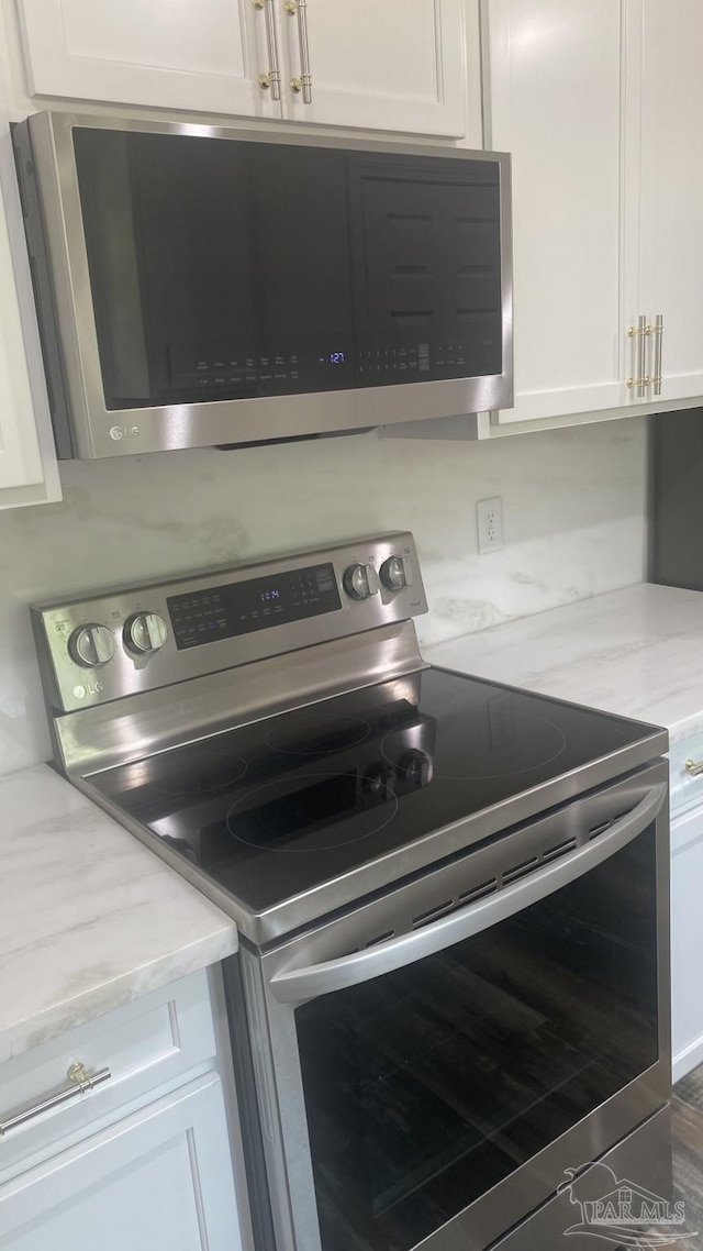room details featuring white cabinetry, appliances with stainless steel finishes, and light stone countertops