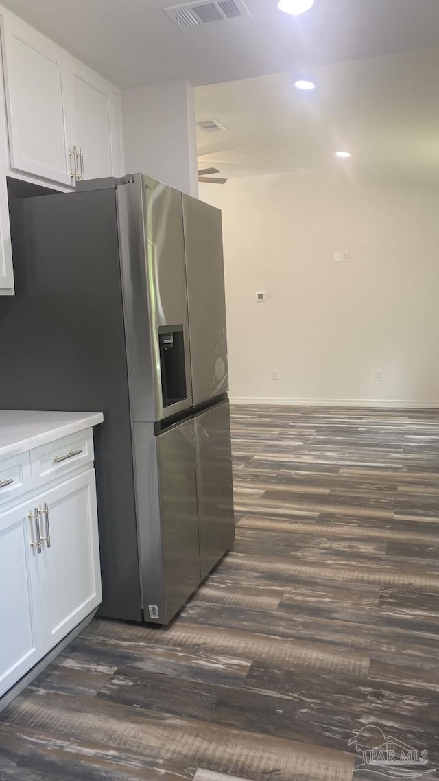 kitchen with stainless steel refrigerator with ice dispenser, visible vents, light countertops, dark wood-style floors, and white cabinetry