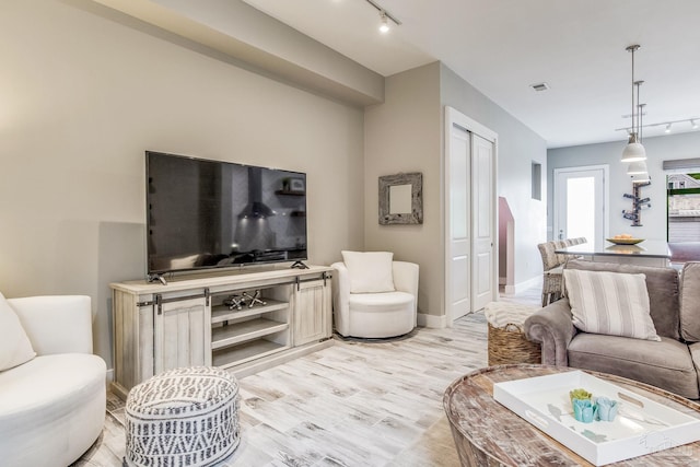 living room featuring track lighting, light wood-type flooring, and baseboards