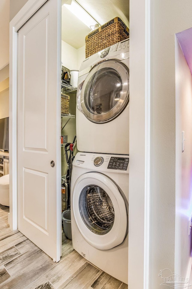 laundry area featuring laundry area, stacked washer and clothes dryer, and light wood-type flooring