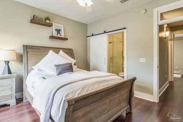 bedroom with a barn door, baseboards, and wood finished floors