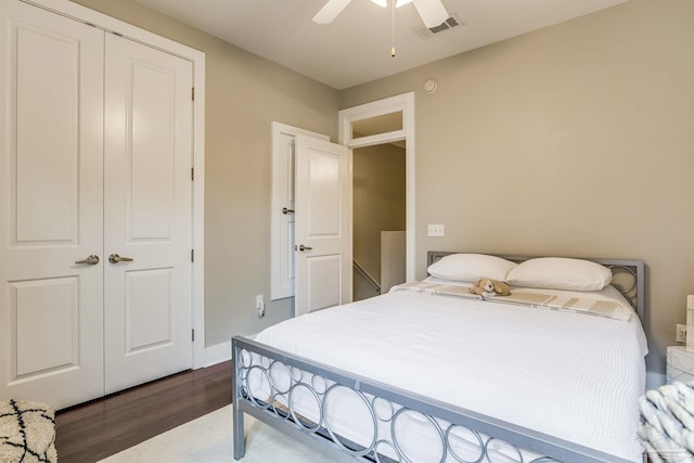 bedroom featuring a ceiling fan, visible vents, baseboards, dark wood-type flooring, and a closet