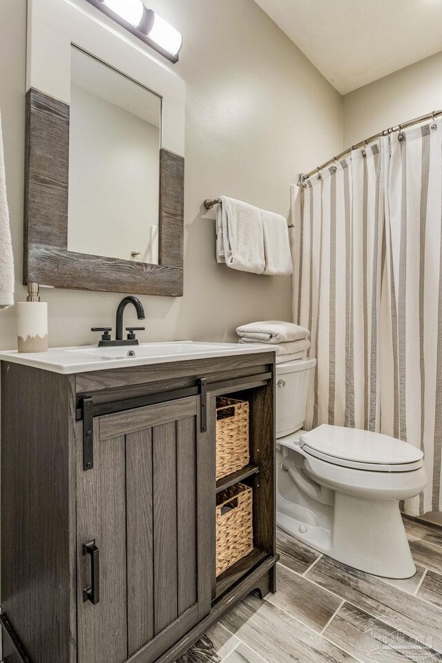 bathroom with a shower with shower curtain, toilet, vanity, and wood tiled floor