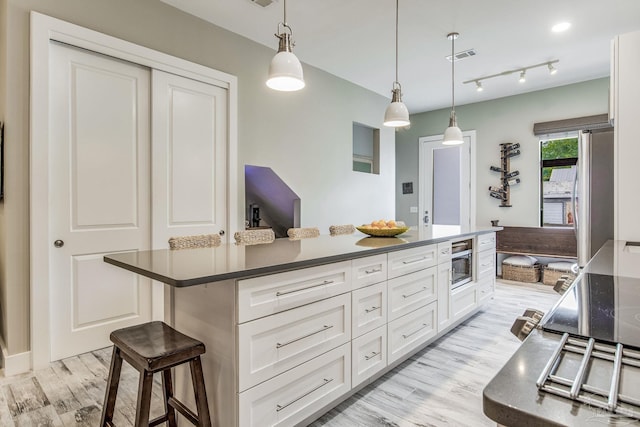 kitchen with dark countertops, white cabinets, light wood-style flooring, and visible vents