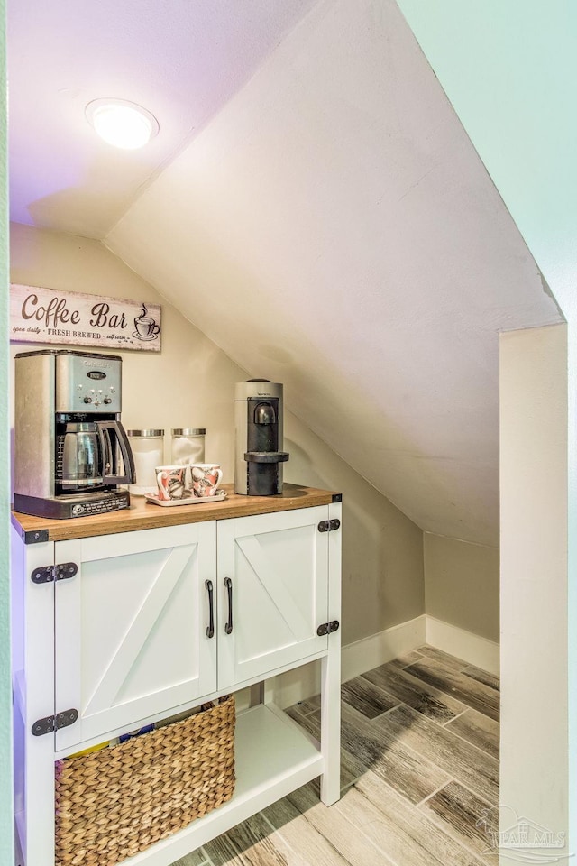 interior space with baseboards, light wood-type flooring, and lofted ceiling