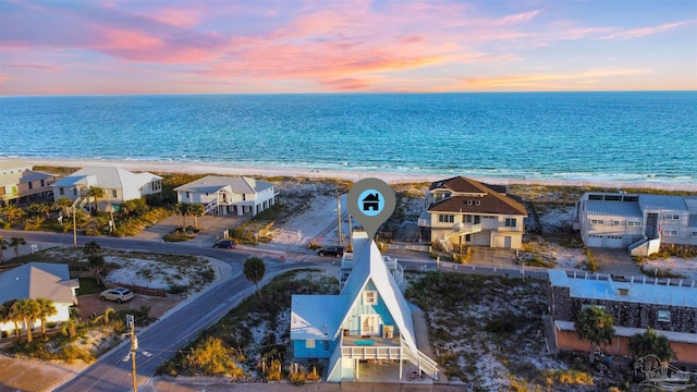 aerial view at dusk with a water view and a view of the beach