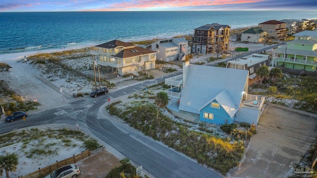 aerial view at dusk with a water view and a beach view