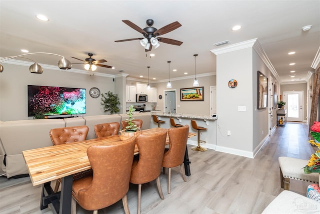 dining area with ceiling fan, light hardwood / wood-style floors, and ornamental molding