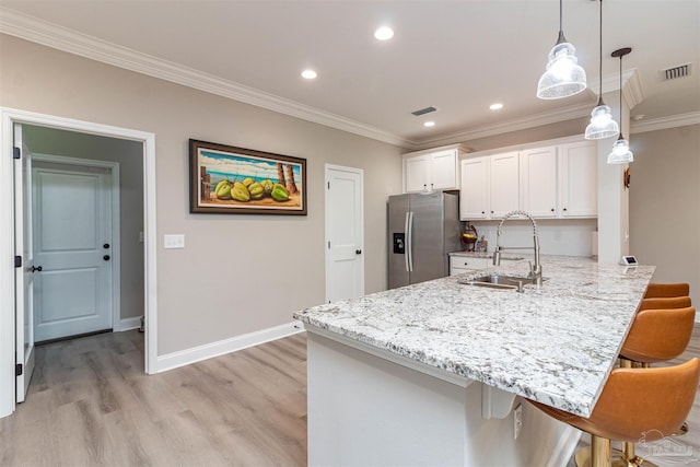 kitchen with stainless steel fridge with ice dispenser, ornamental molding, a kitchen bar, white cabinets, and sink