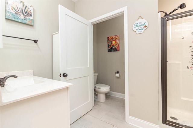 bathroom with a shower with door, vanity, tile patterned floors, and toilet