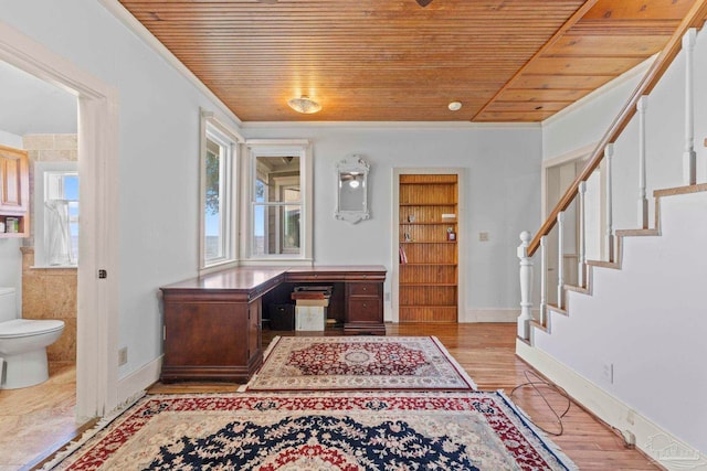 foyer with wooden ceiling, crown molding, stairs, baseboards, and wood finished floors