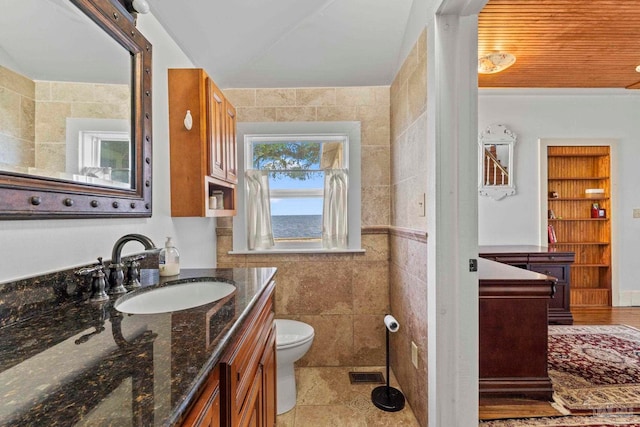 bathroom with tile walls, visible vents, toilet, and vanity