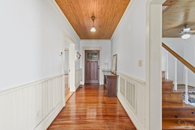 hallway featuring stairs, wood ceiling, ornamental molding, wainscoting, and wood finished floors