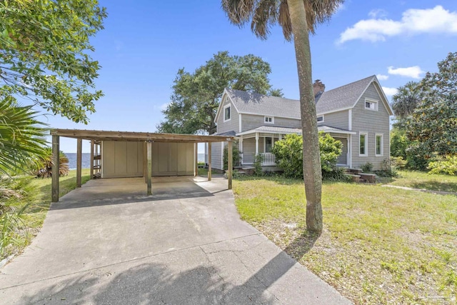 view of home's exterior featuring driveway, a carport, a chimney, roof with shingles, and a lawn