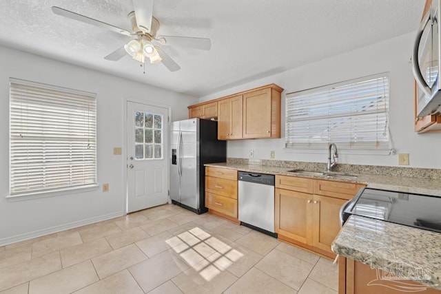 kitchen with light brown cabinetry, stainless steel appliances, ceiling fan, sink, and light tile patterned floors