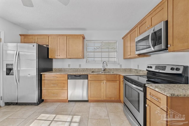 kitchen featuring light stone counters, a textured ceiling, stainless steel appliances, sink, and light tile patterned floors