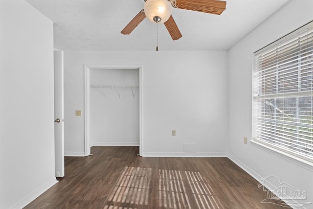 unfurnished bedroom featuring dark hardwood / wood-style flooring, ceiling fan, and a closet