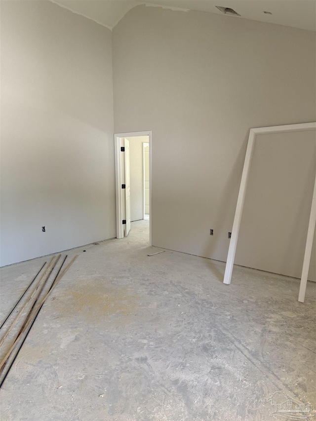 unfurnished room with visible vents and high vaulted ceiling