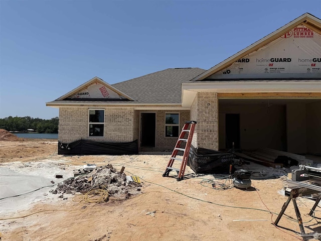 property in mid-construction with brick siding and a shingled roof