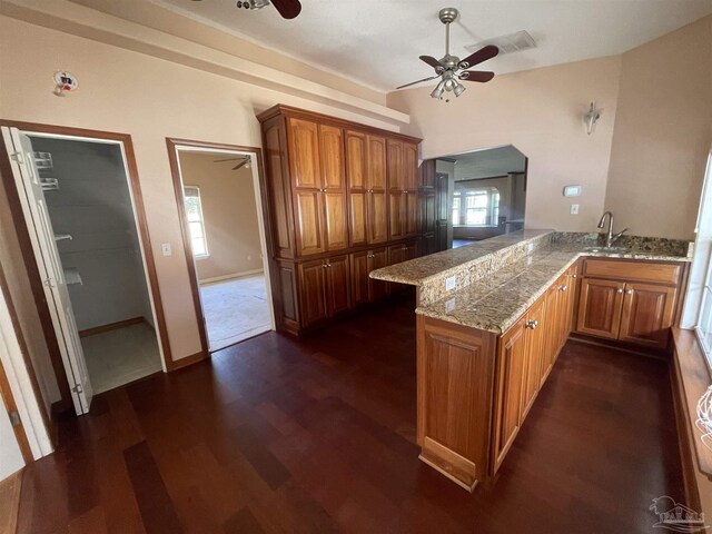 kitchen with ceiling fan, dark hardwood / wood-style flooring, kitchen peninsula, and sink