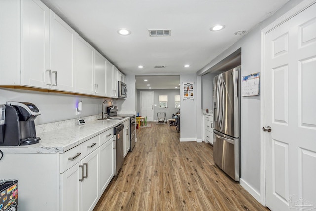 kitchen with sink, light hardwood / wood-style flooring, white cabinets, and appliances with stainless steel finishes