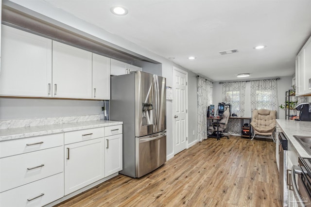 kitchen with white cabinetry, light hardwood / wood-style flooring, stainless steel appliances, and light stone counters