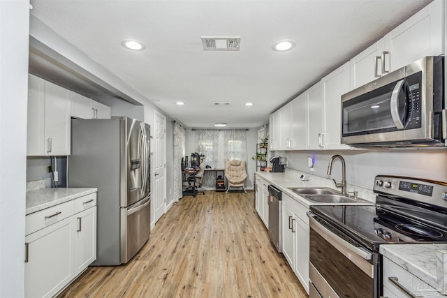 kitchen with light wood-type flooring, white cabinetry, sink, and appliances with stainless steel finishes