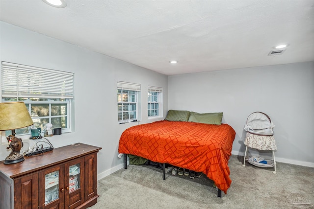 carpeted bedroom featuring a textured ceiling and multiple windows