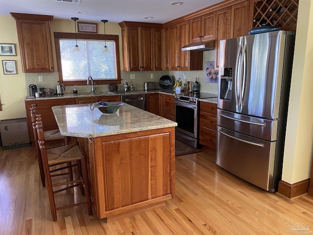 kitchen with a kitchen island, sink, stainless steel appliances, and hanging light fixtures