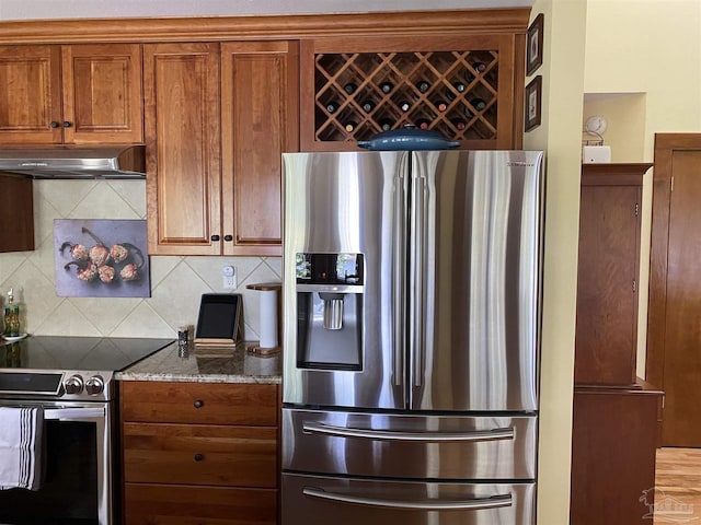 kitchen featuring stainless steel appliances, light stone counters, and tasteful backsplash