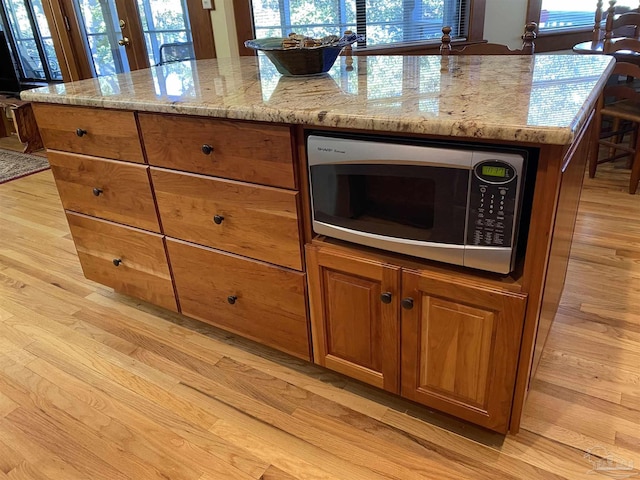 kitchen with light stone counters, a kitchen island, and light wood-type flooring