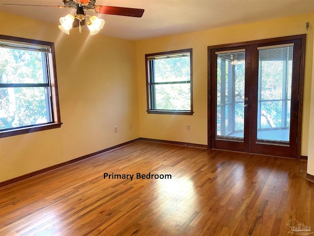 spare room featuring plenty of natural light, ceiling fan, wood-type flooring, and french doors