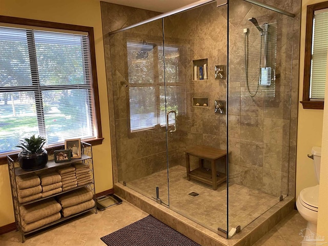 bathroom with toilet, tile patterned floors, an enclosed shower, and a healthy amount of sunlight