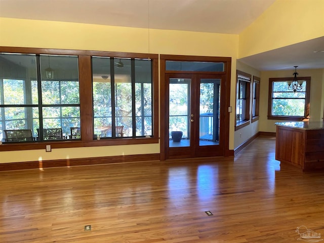 interior space with a healthy amount of sunlight, french doors, wood-type flooring, and a notable chandelier