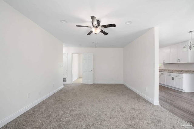 unfurnished living room featuring ceiling fan and light carpet