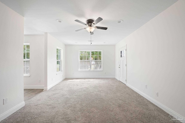 empty room with carpet flooring, ceiling fan, and baseboards