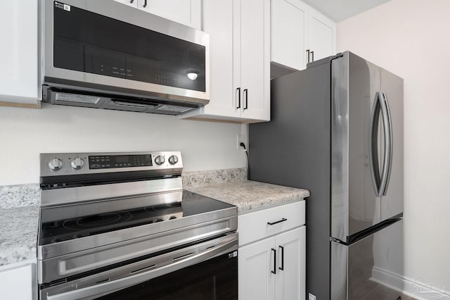 kitchen with white cabinets, appliances with stainless steel finishes, and baseboards