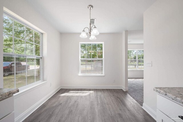 unfurnished dining area with a chandelier and dark hardwood / wood-style floors