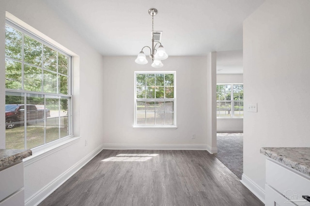 unfurnished dining area with visible vents, baseboards, a chandelier, and dark wood-style flooring