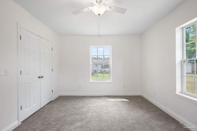 carpeted empty room with a healthy amount of sunlight and ceiling fan