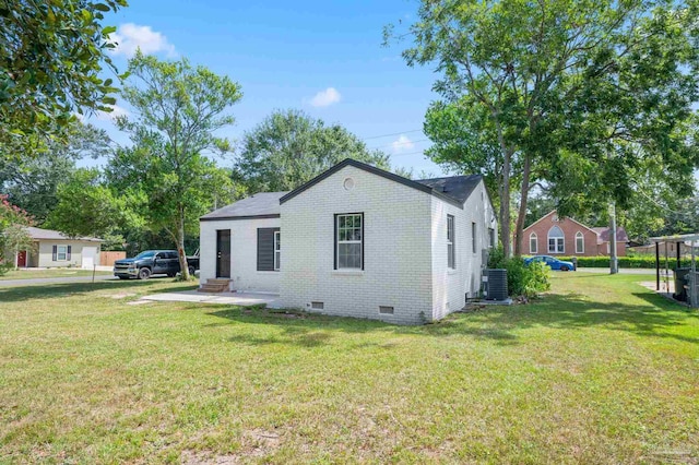 rear view of property featuring crawl space, brick siding, cooling unit, and a lawn