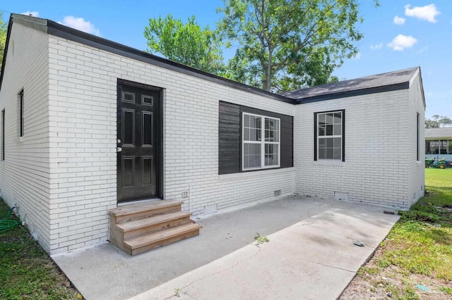 exterior space with crawl space, brick siding, and a patio area